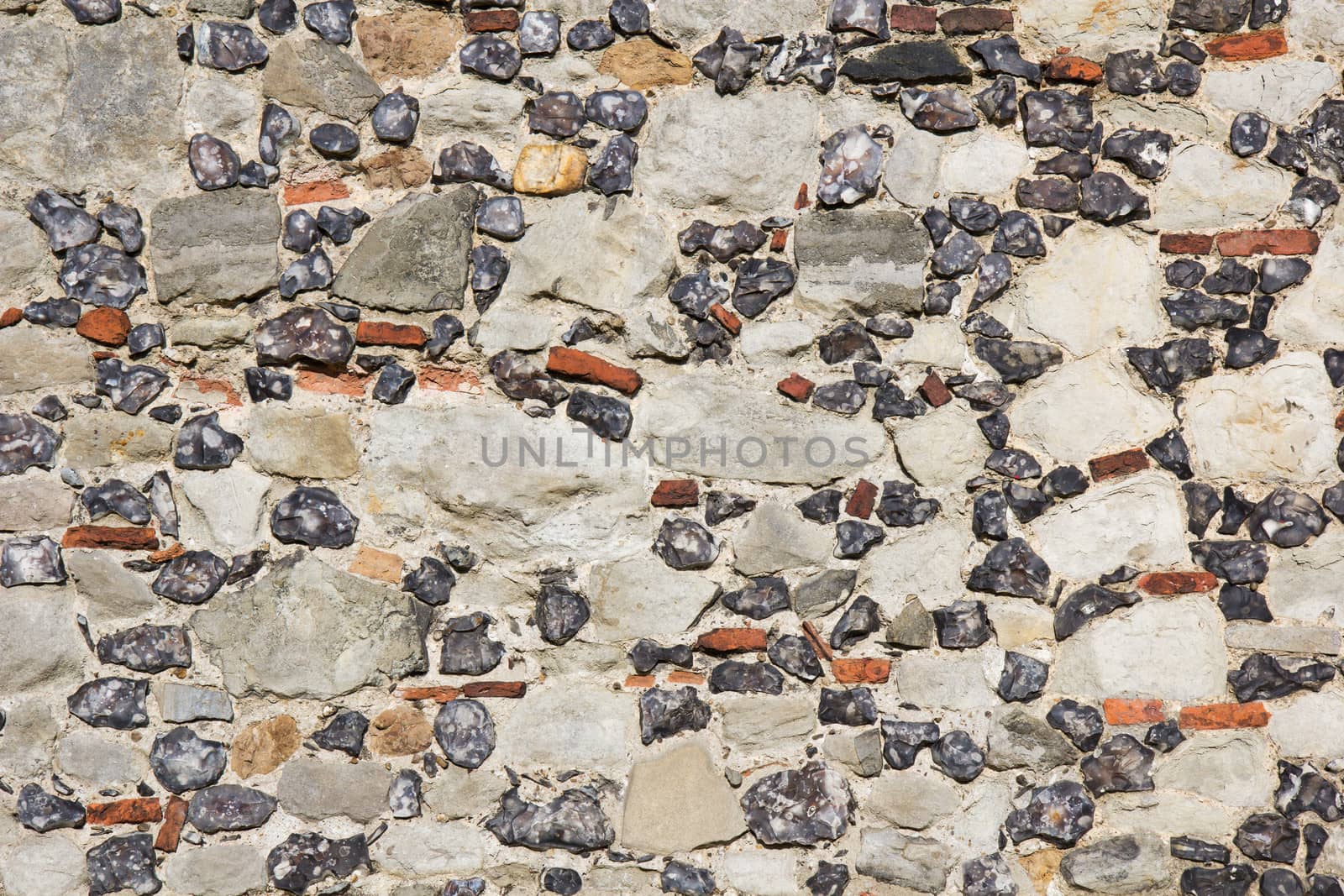 Multicoloured stone background of a building exterior facade with different sizes, colours and textures of stones.