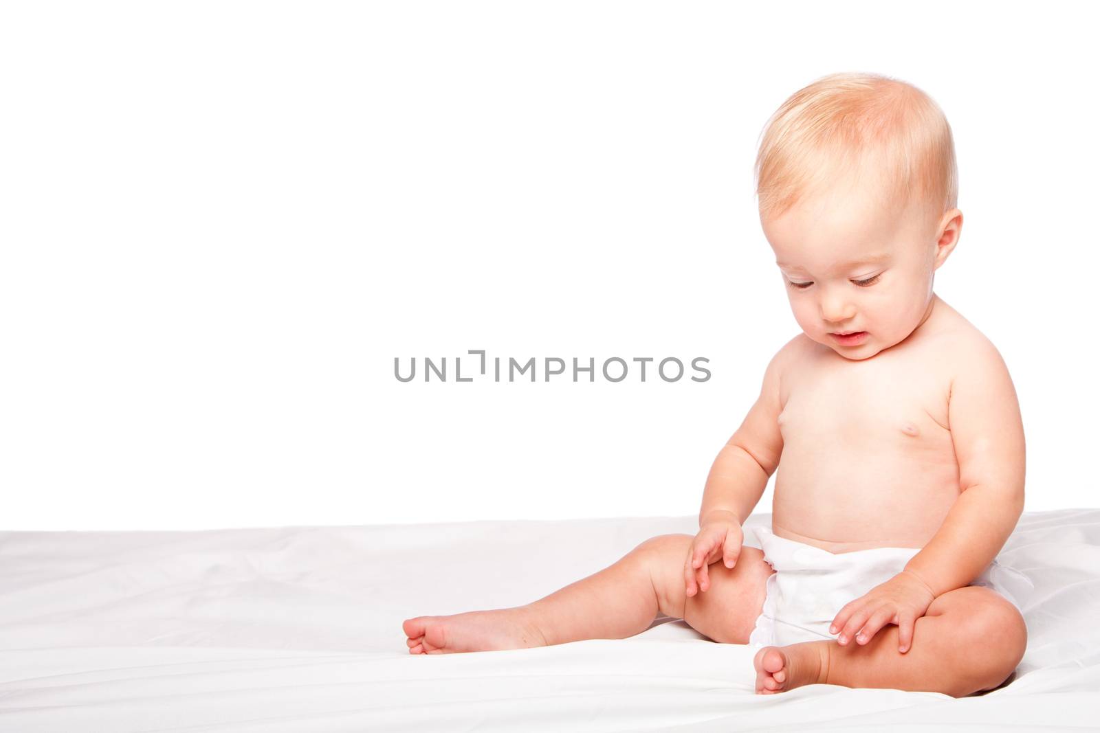 Cute adorable infant baby sitting alone, on white.