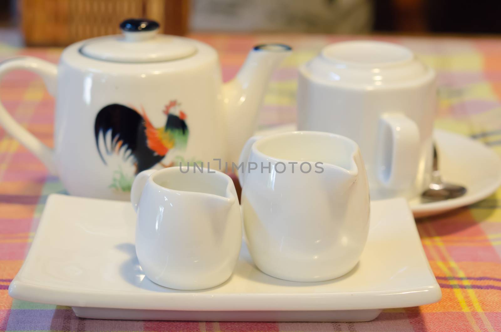 White milk pitcher on white plate ,  teapot and cup on dish