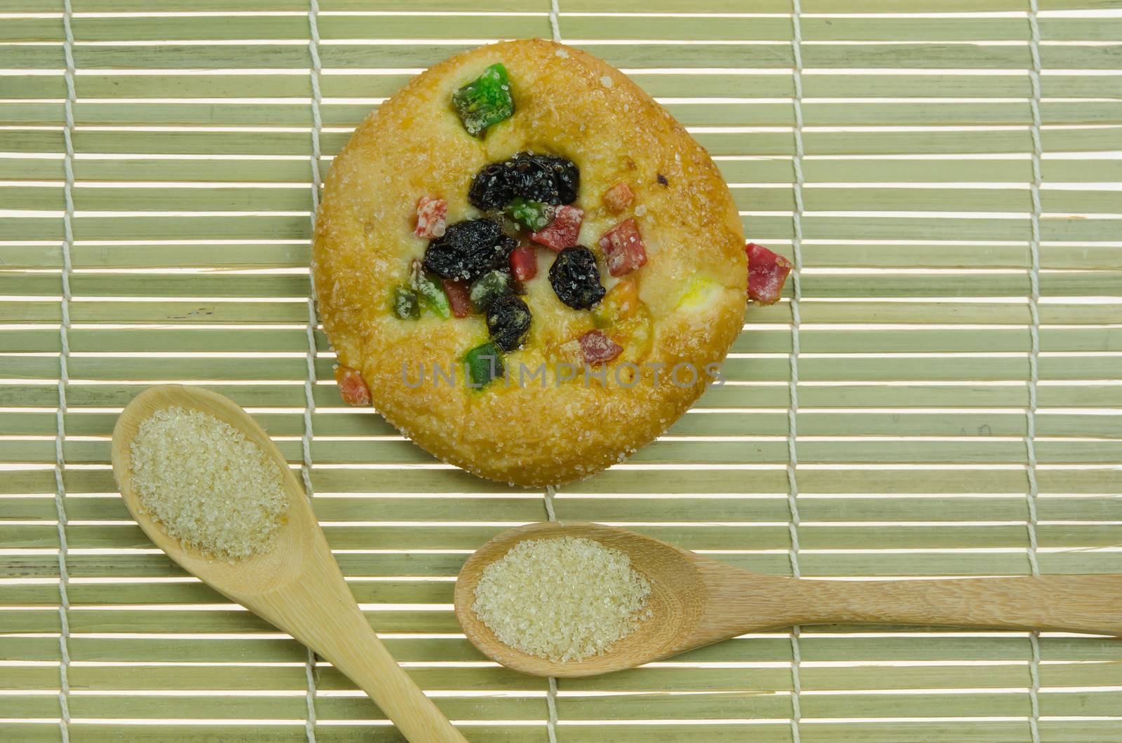 top view of  bread with raisin and  dried fruits and two spoon of sugar on wooden background 