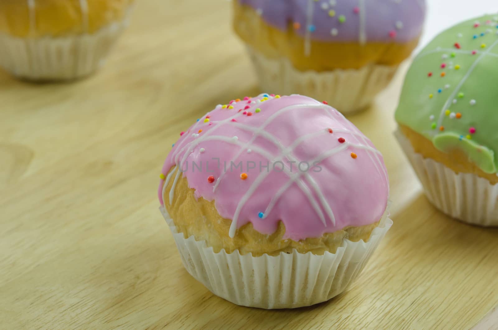 close up  cupcake with colorful sprinkles on wooden board