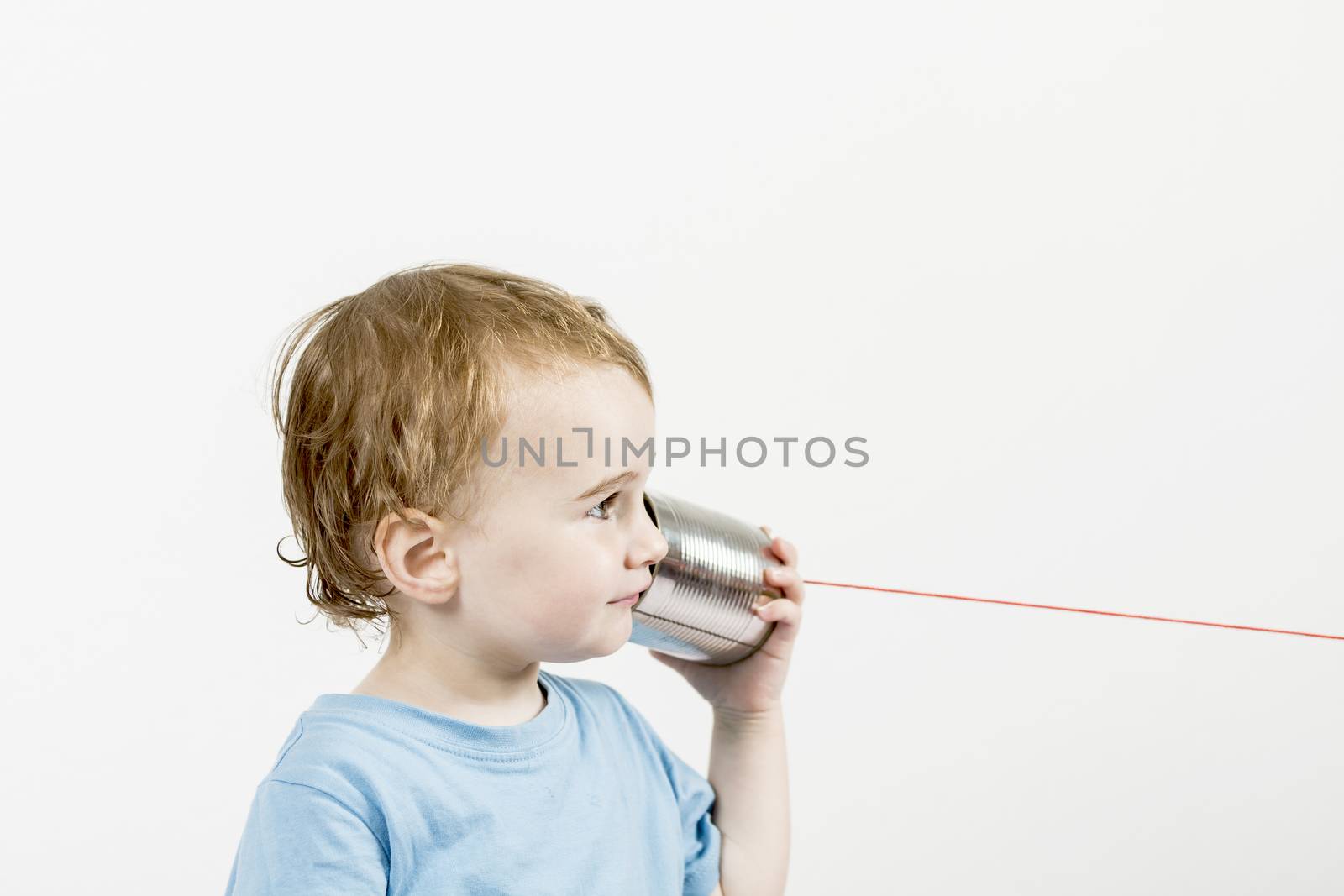 young child in grey background listening to tin can phone. horizontal image