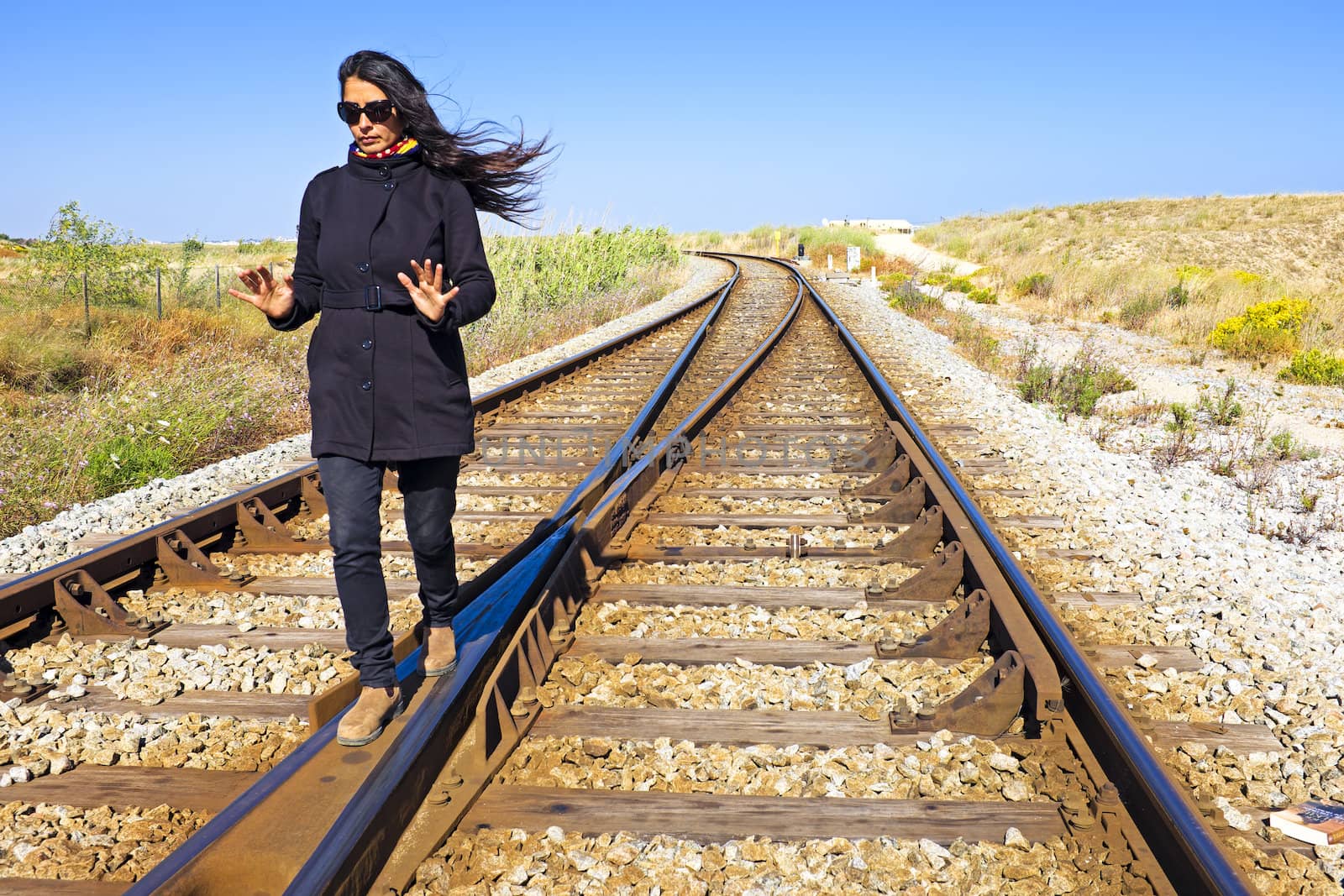 Young beautiful woman walking on a railroad track