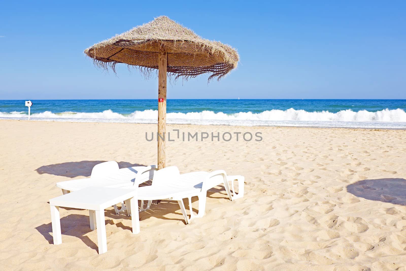 Thatched umbrella and beach chairs on the beach near Lagos Portugal