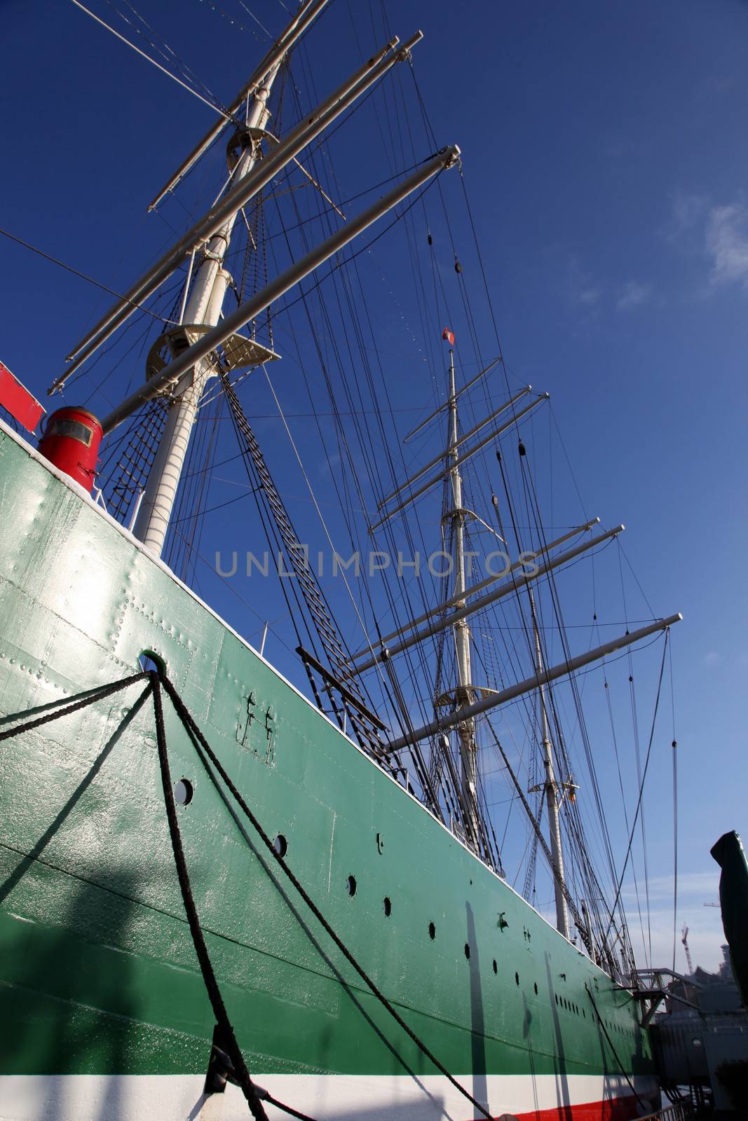 View along the hull of a tall ship in harbour looking up towards the twin masts and rigging