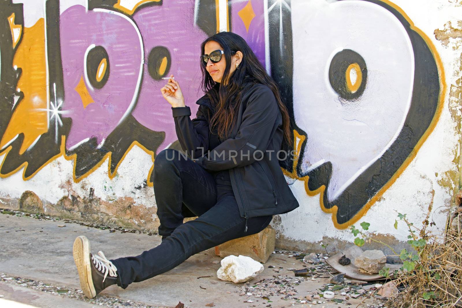 Young beautiful woman smoking in front of a graffiti wall
