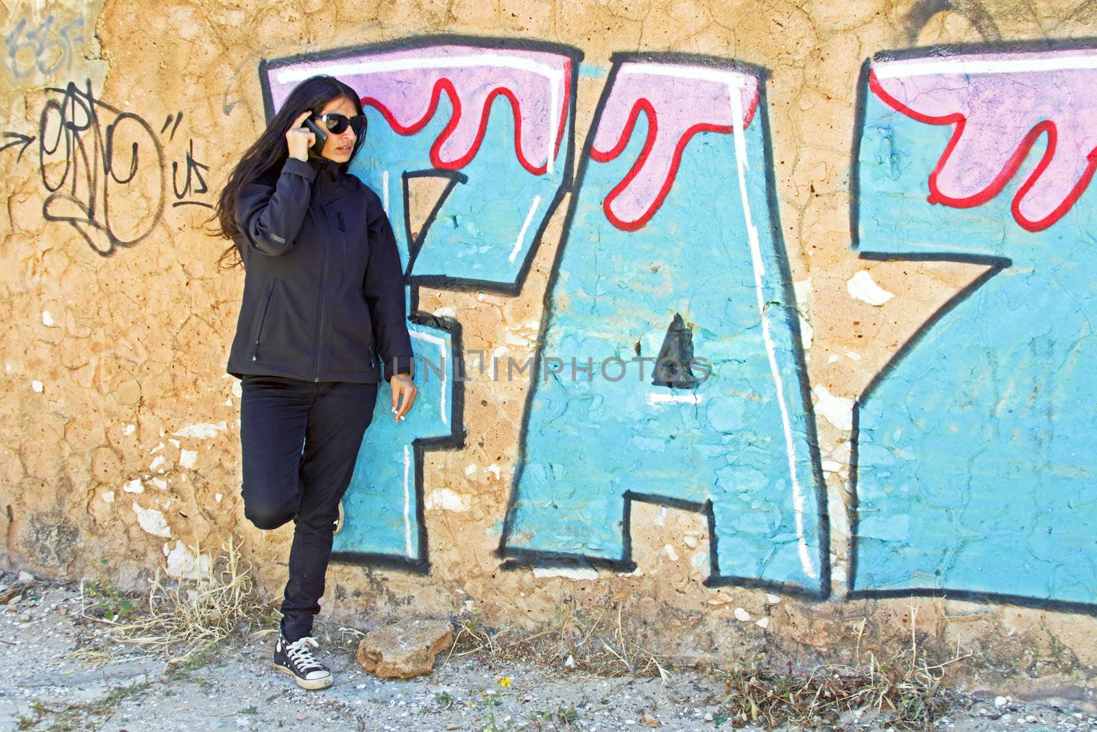 Smoking woman phoning at a graffiti wall