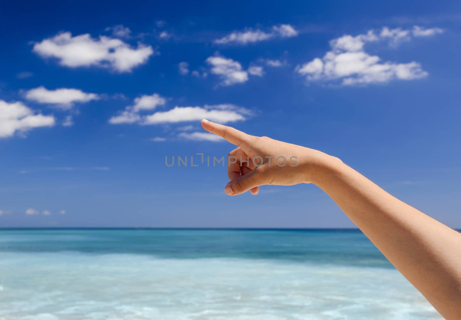 Female hand against a beautiful blue sky pointing somewhere