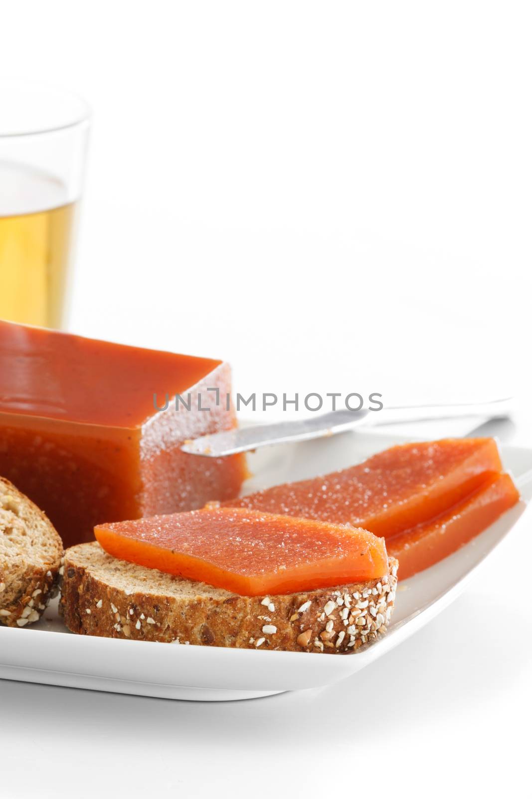 Quince jam slices on seeds bread on a plate over a white background.