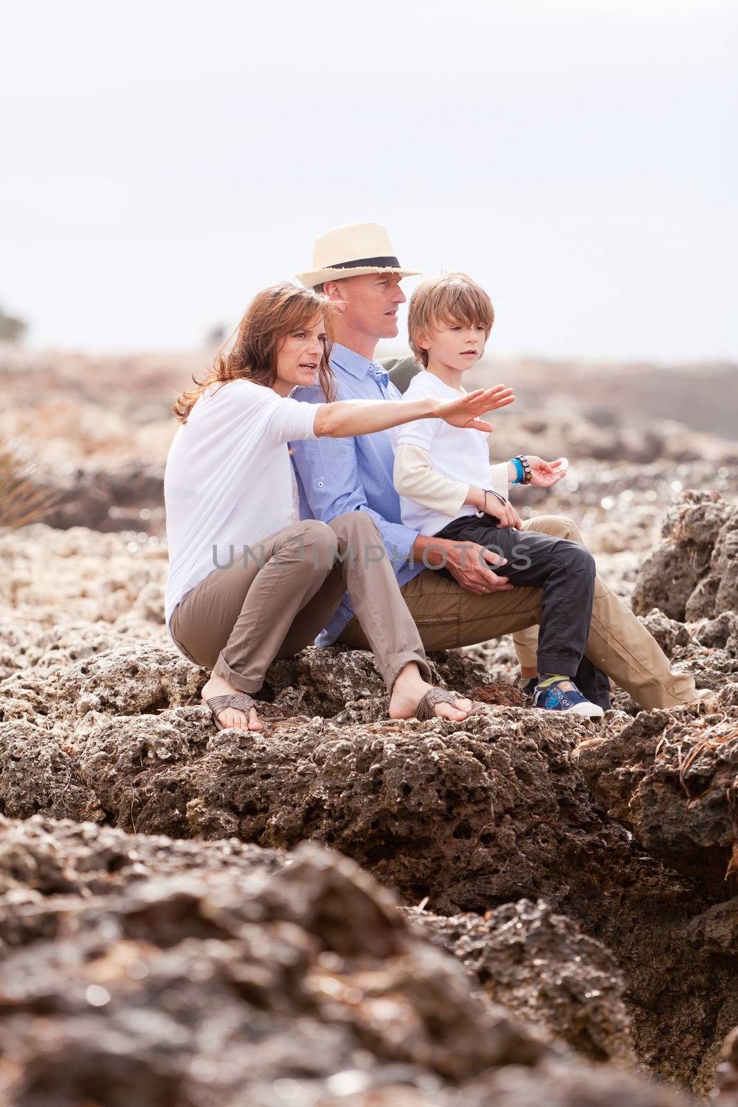 happy family sitting on rock and watching the ocean waves holiday 