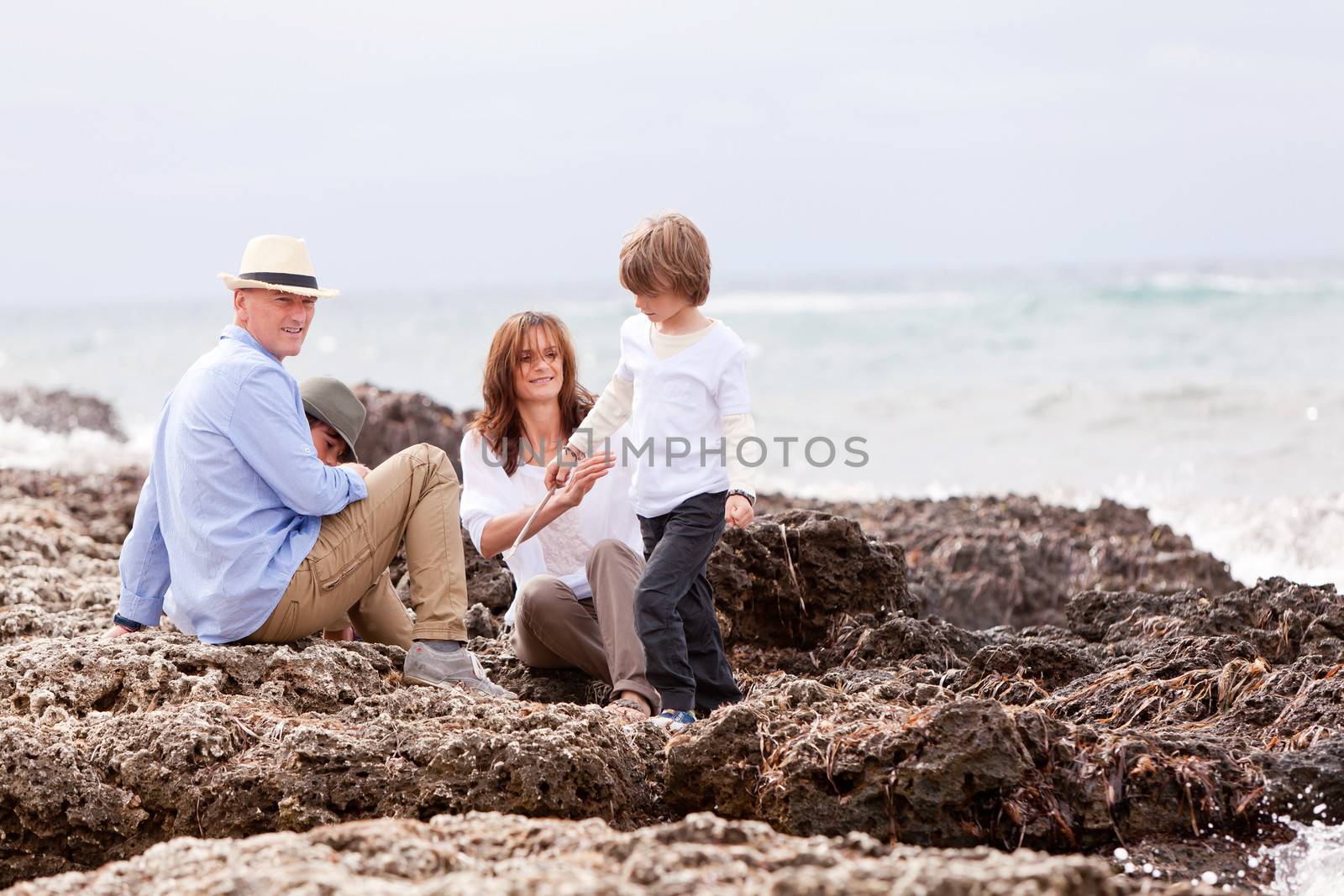 happy family sitting on rock and watching the ocean waves holiday 