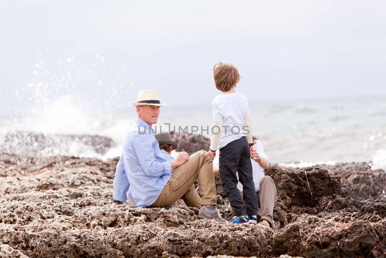 happy family sitting on rock and watching the ocean waves holiday 