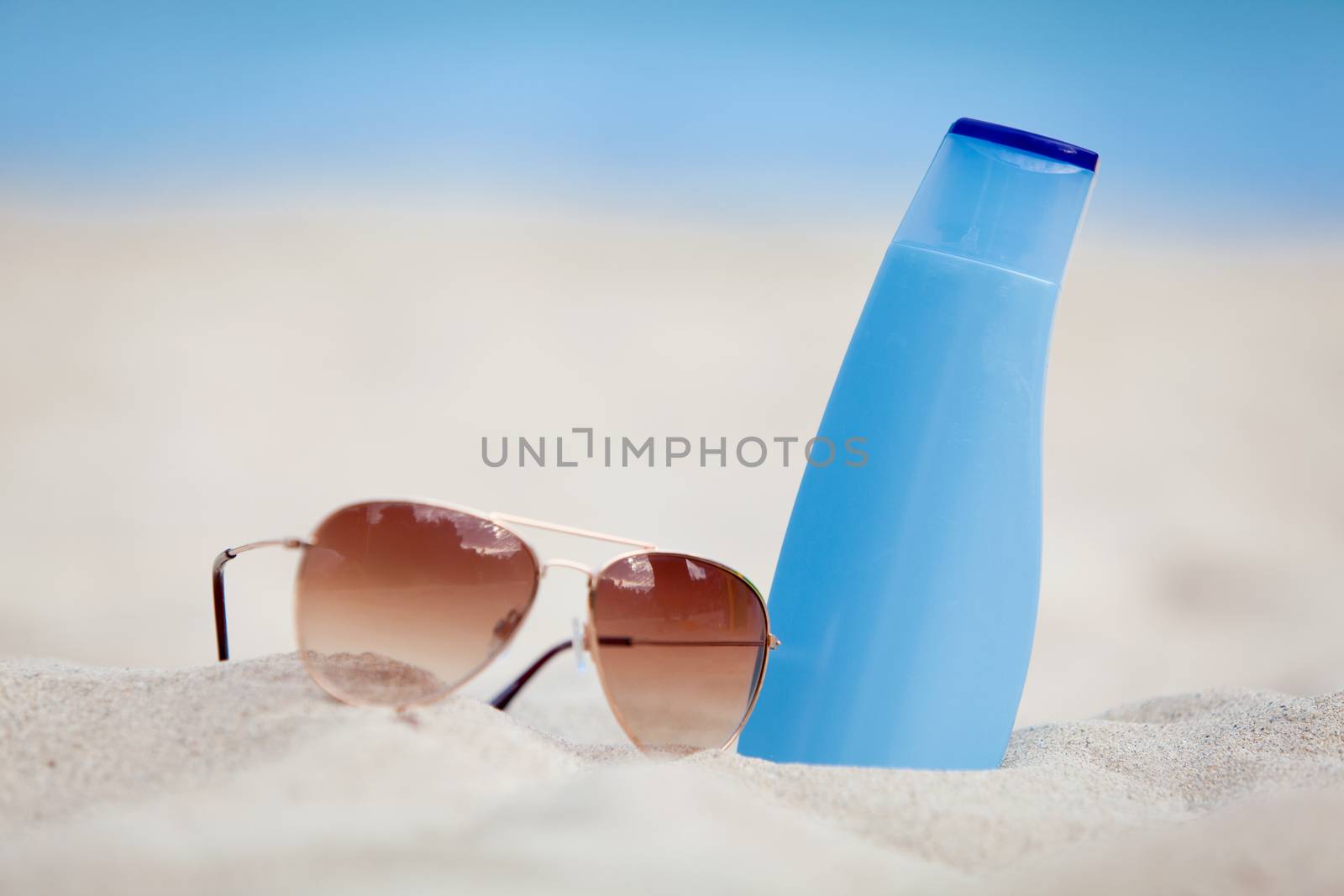 sunprotection summer holiday sunglasses and cream in sand macro