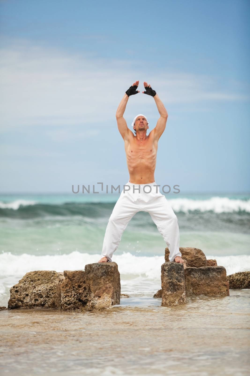 healthy man doing pilates yoga meditation on beach summer freedom