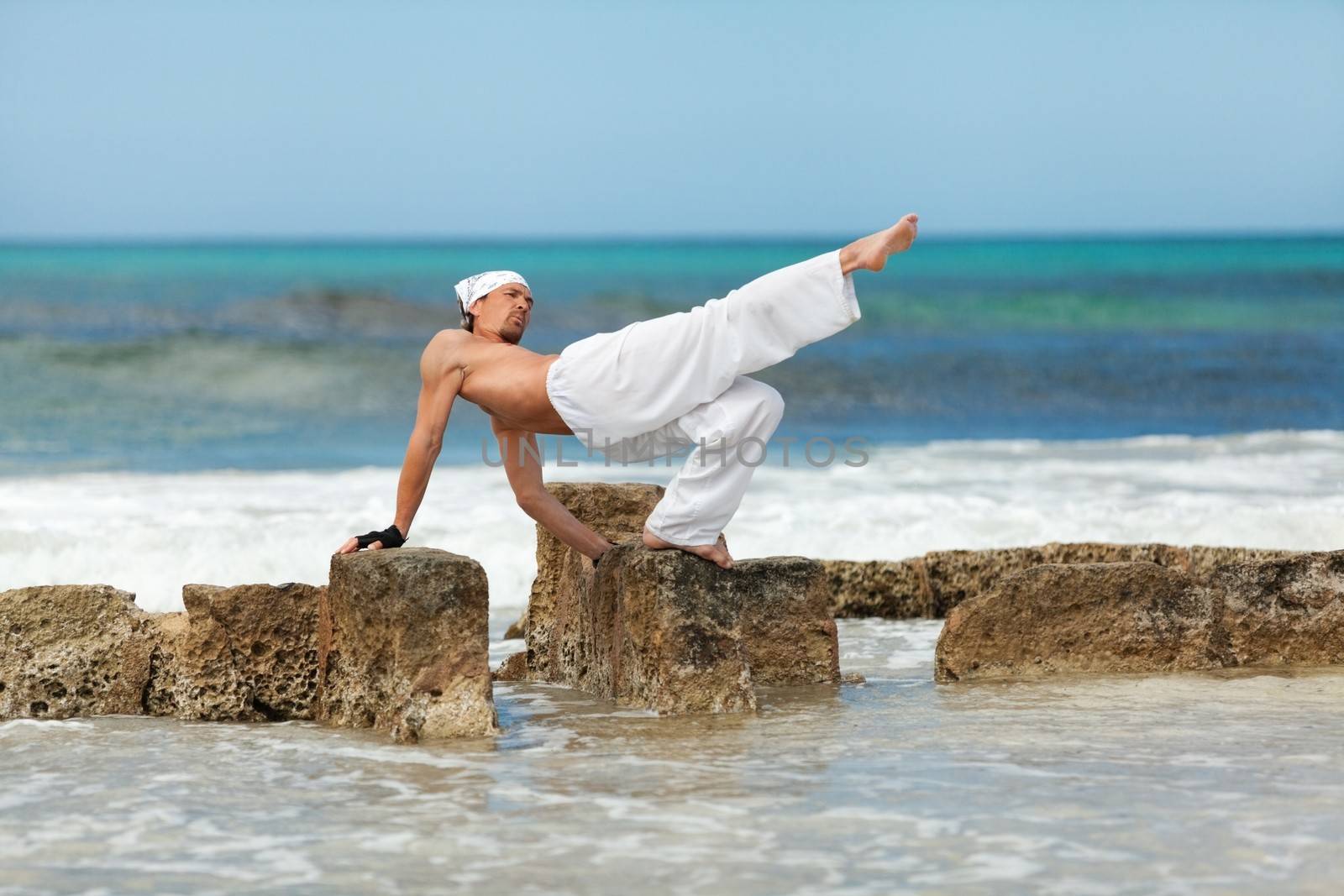 healthy man doing pilates yoga meditation on beach summer freedom