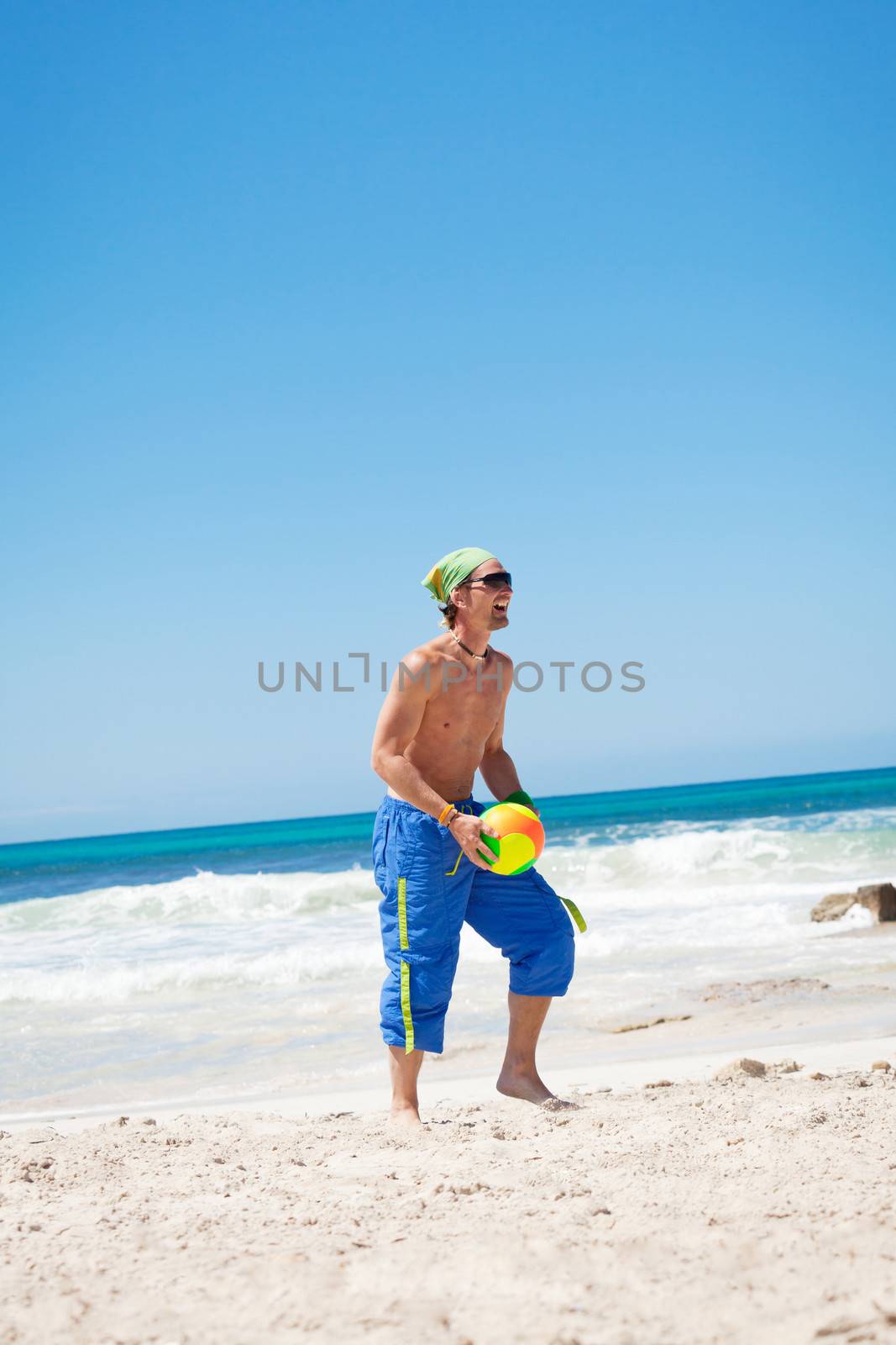 attractive young man playing volleyball on the beach summertime 