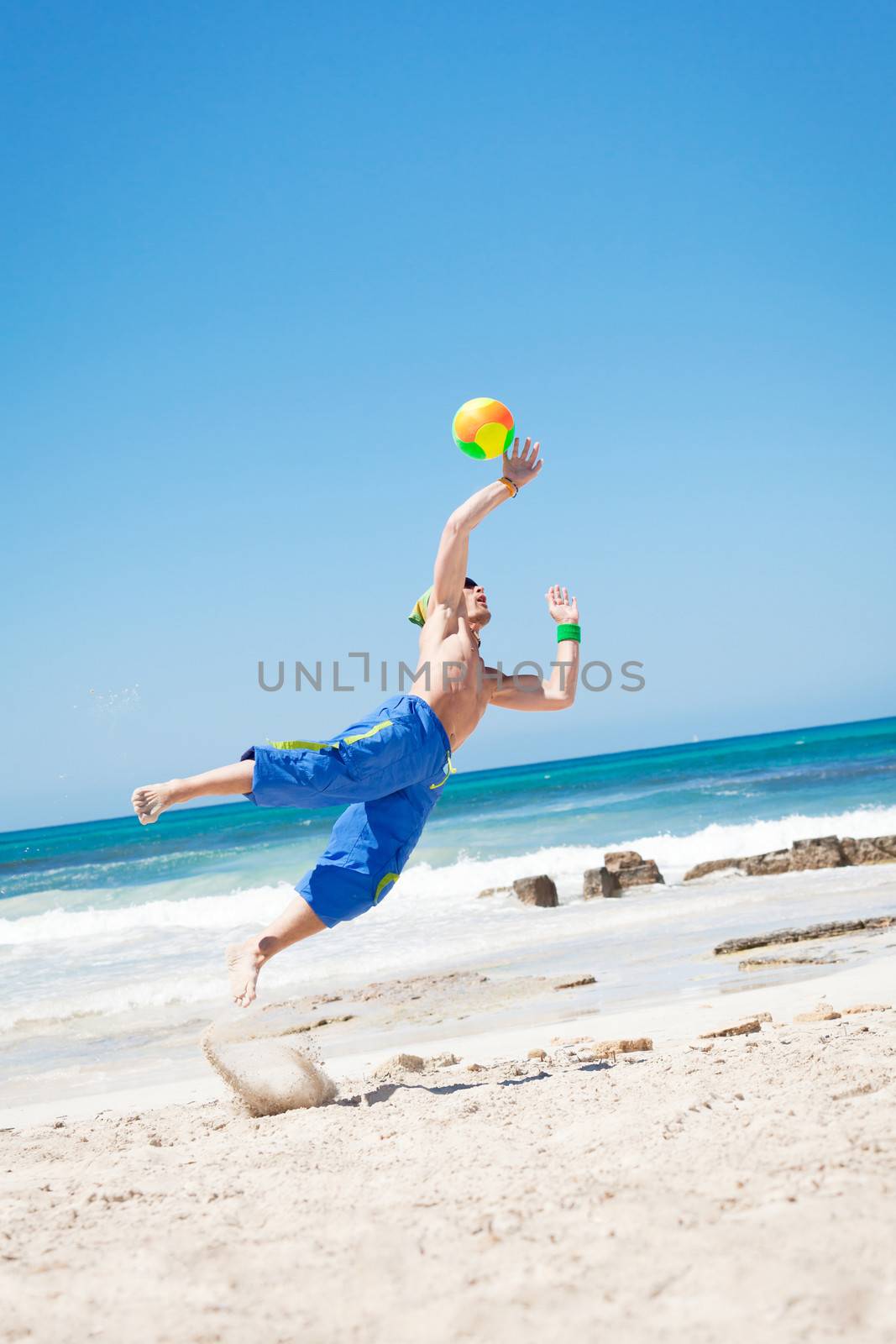 attractive young man playing volleyball on the beach summertime 