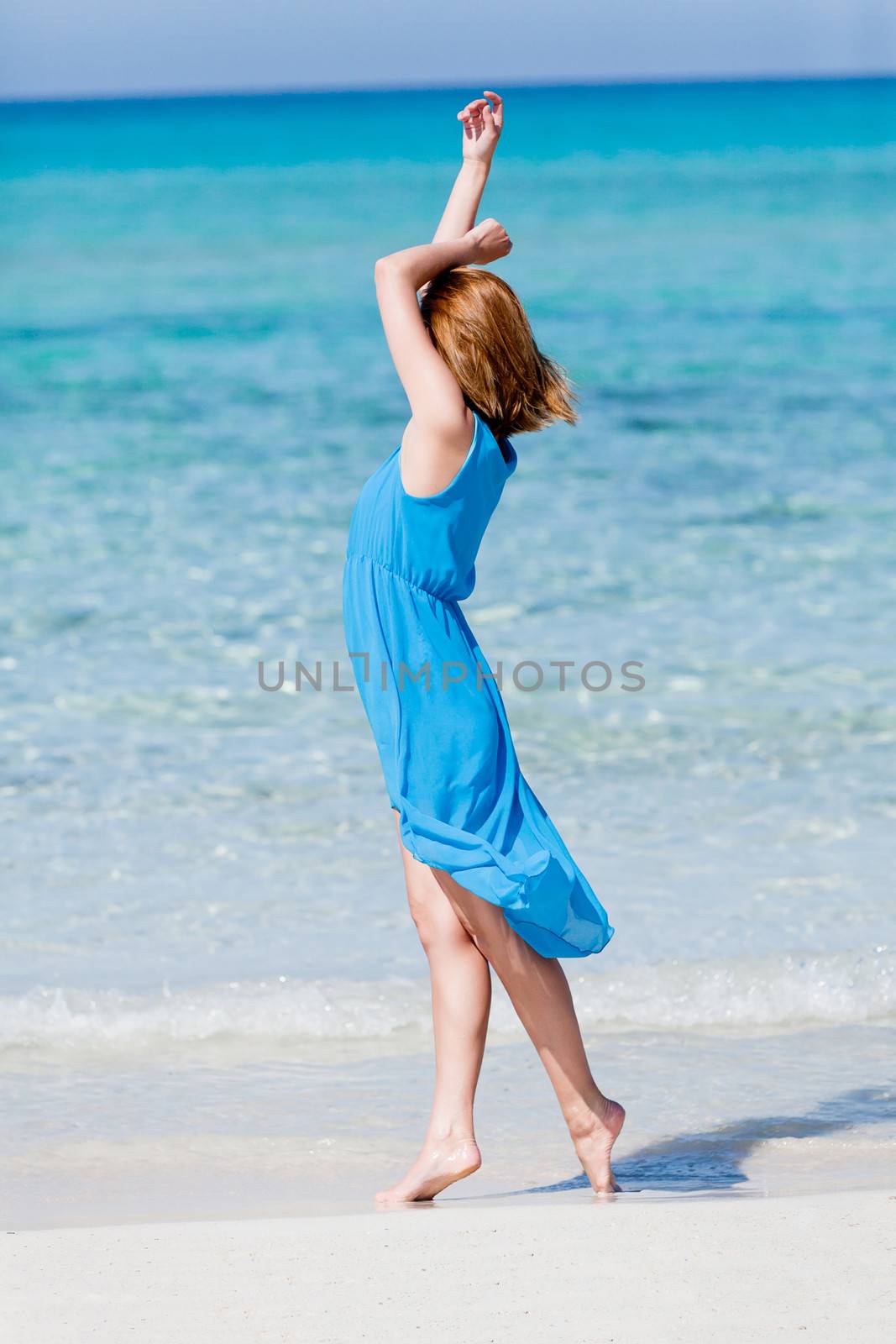 beautiful woman in blue dress on beach in summer holiday carefree