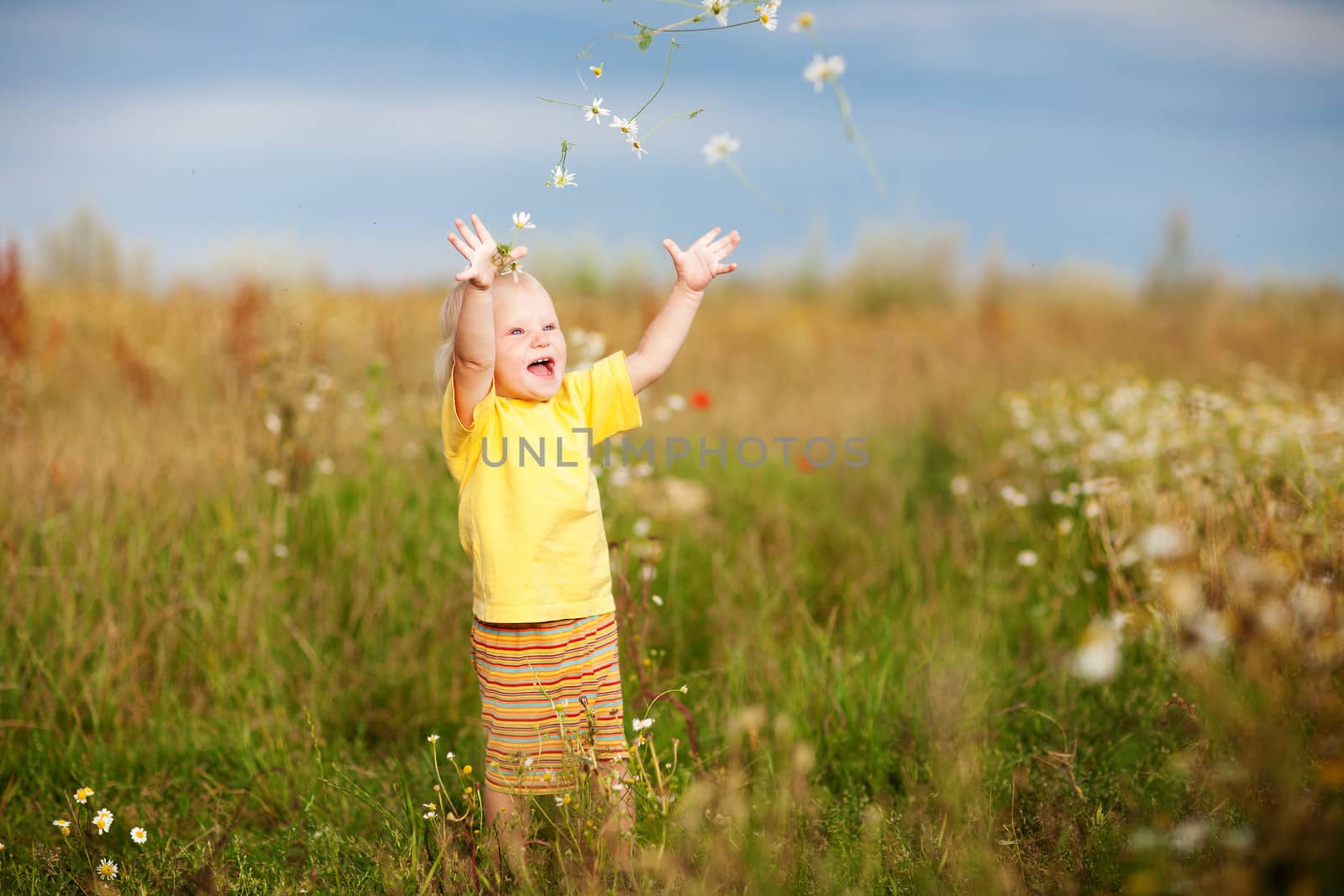 child throwing flowers on the field