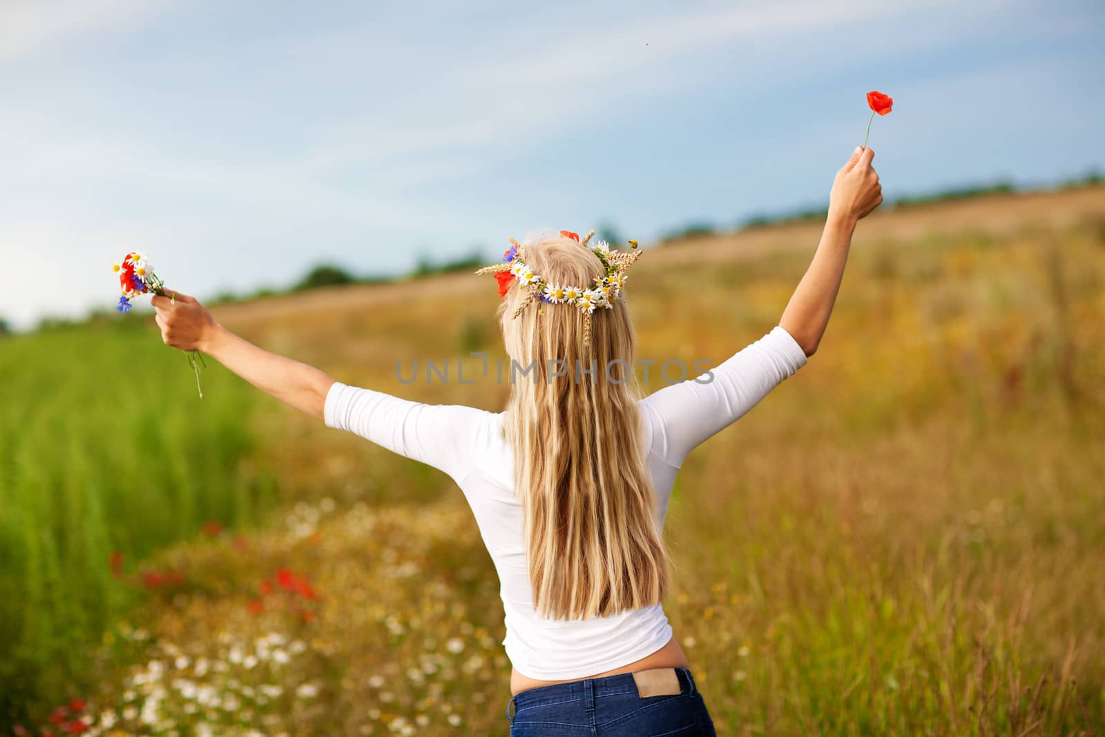 blond girl with flowers on the field