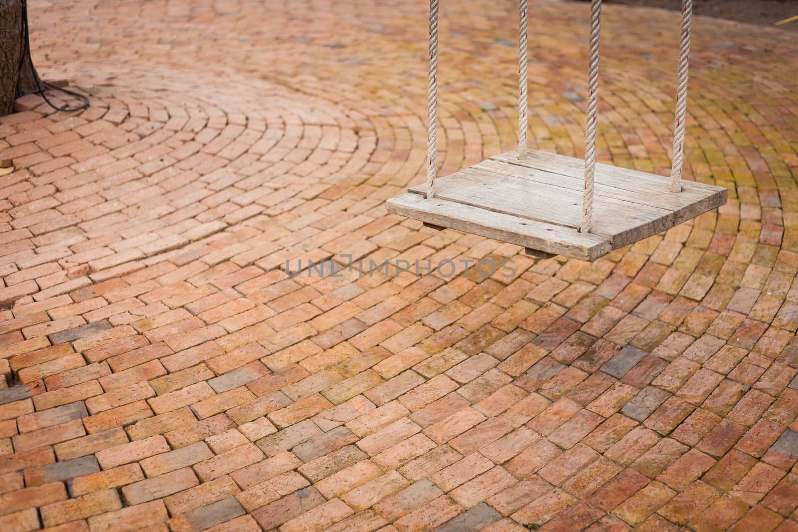 Swing wood in playground with brick floor