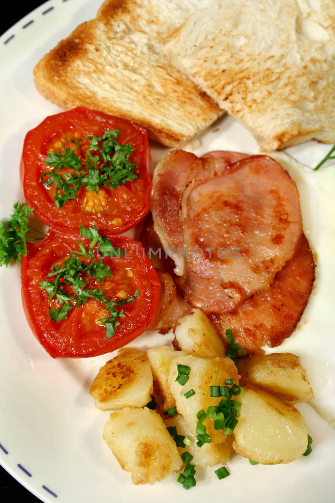 Breakfast of bacon, potato chips and grilled tomato with toast.