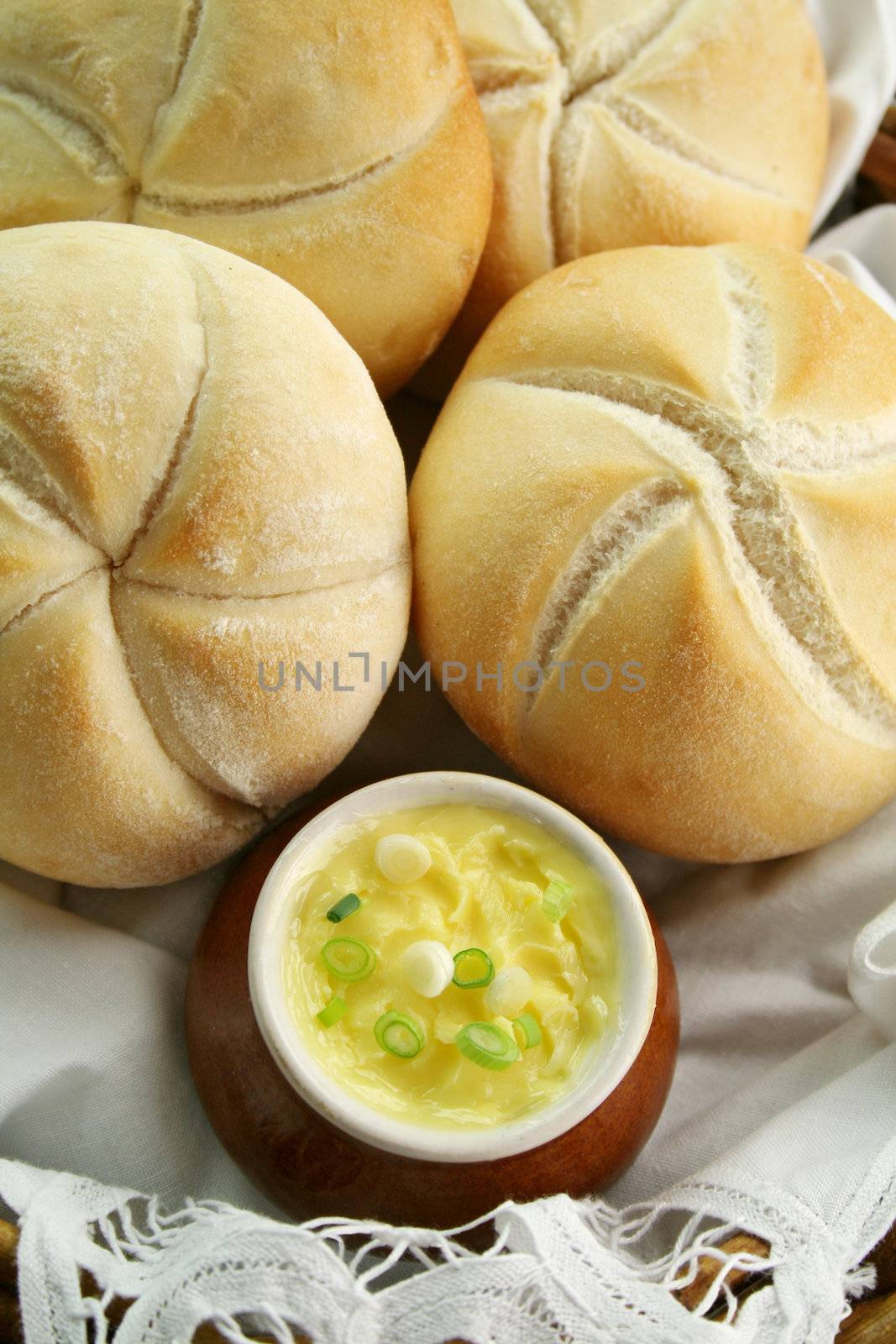 Fresh round breadrolls with a jar of butter and diced spring onions.