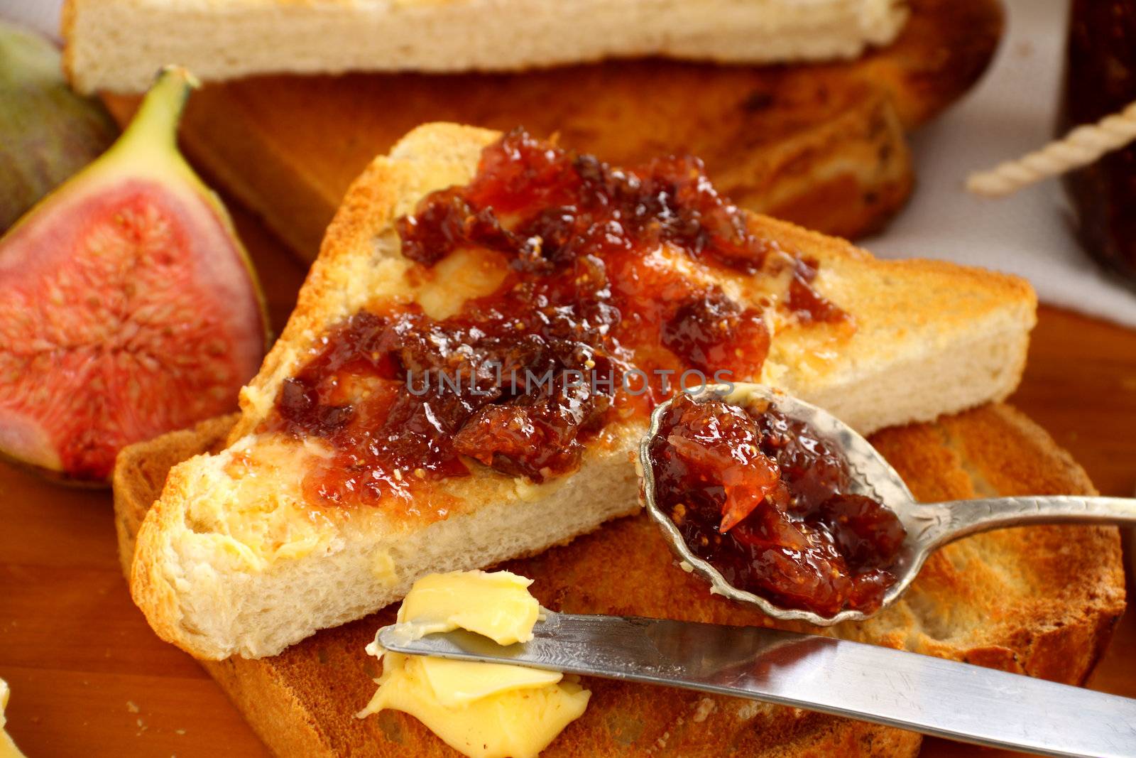 A spoonful of homemade fig jam by a fig jam sandwich.