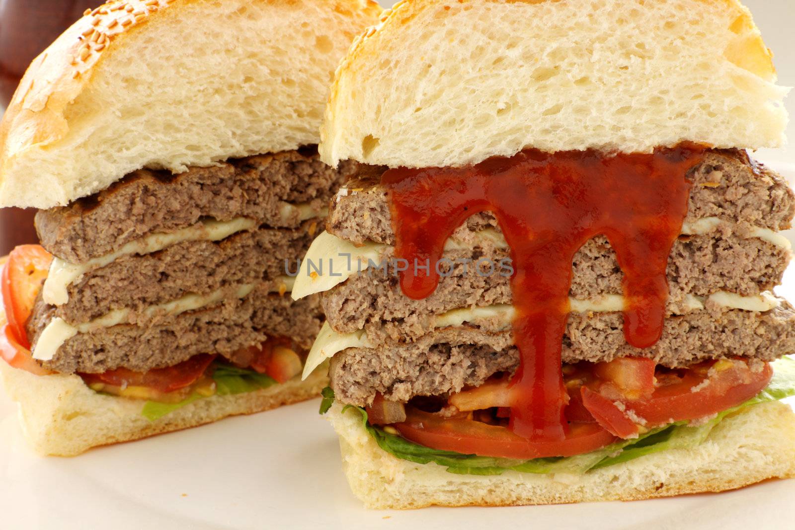 Sliced triple decker beef and cheese burger with ketchup ready to serve.