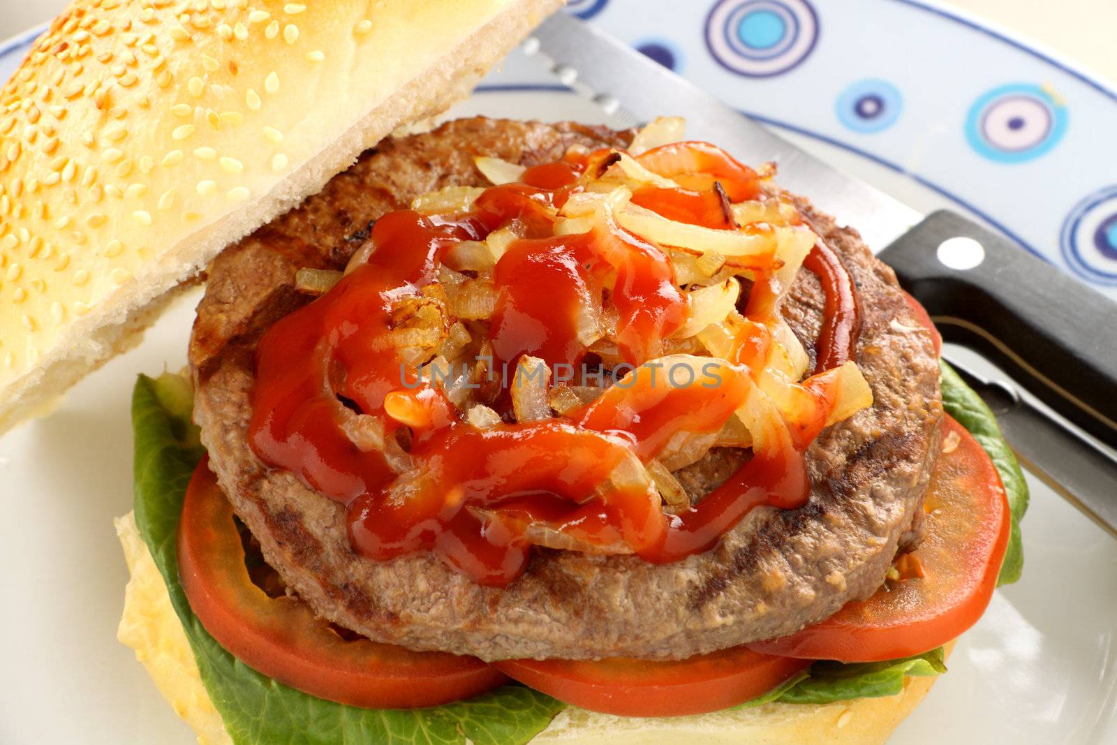 Fried onions on a beef burger with ketchup.