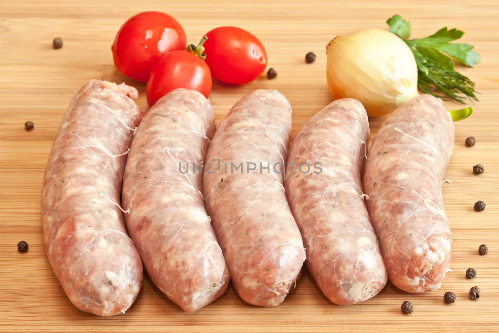 Uncooked sausage with vegetables on the chopping board
