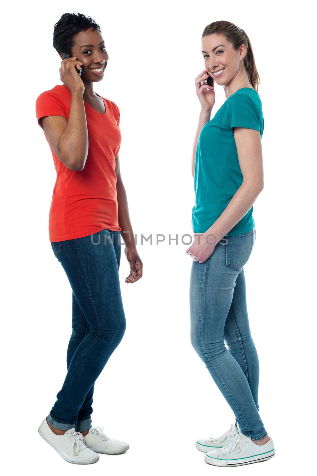 Trendy females speaking over cellphone by stockyimages