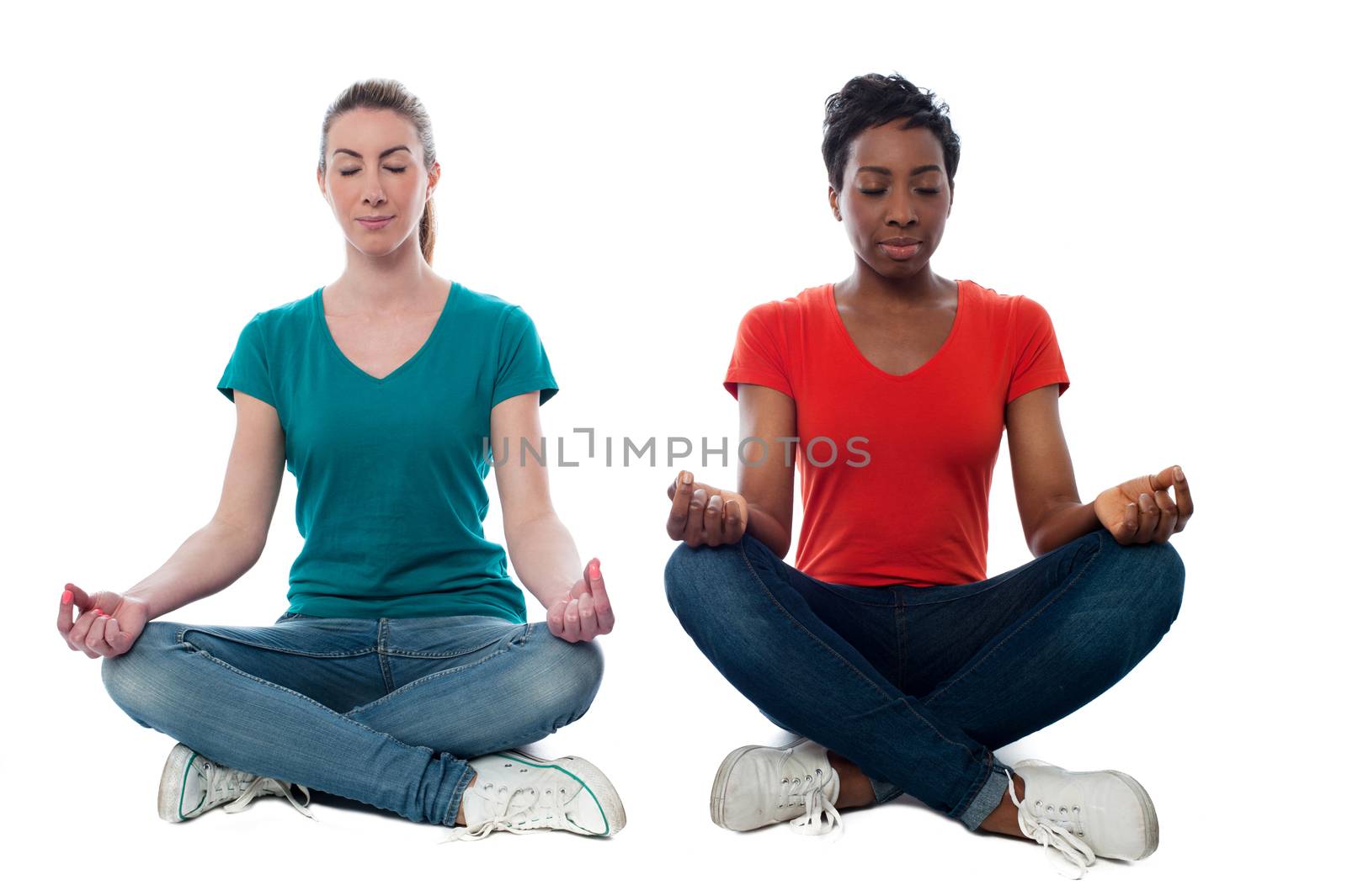 Two beautiful casual women meditating by stockyimages
