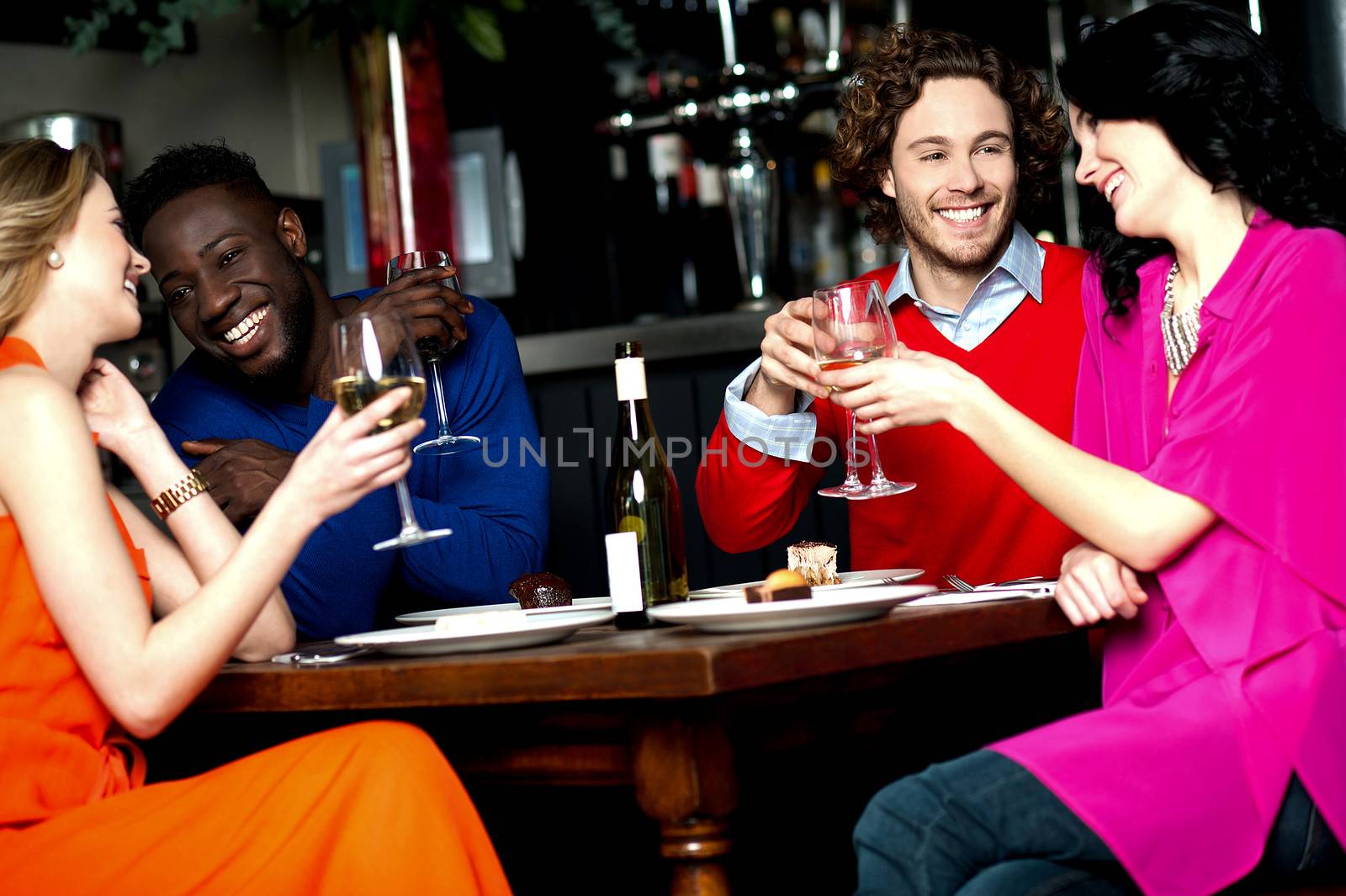 Friends enjoying snacks with drinks in a bar.