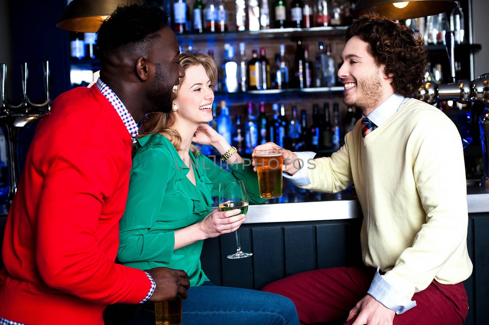 Group of three friends in a bar drinking beer by stockyimages