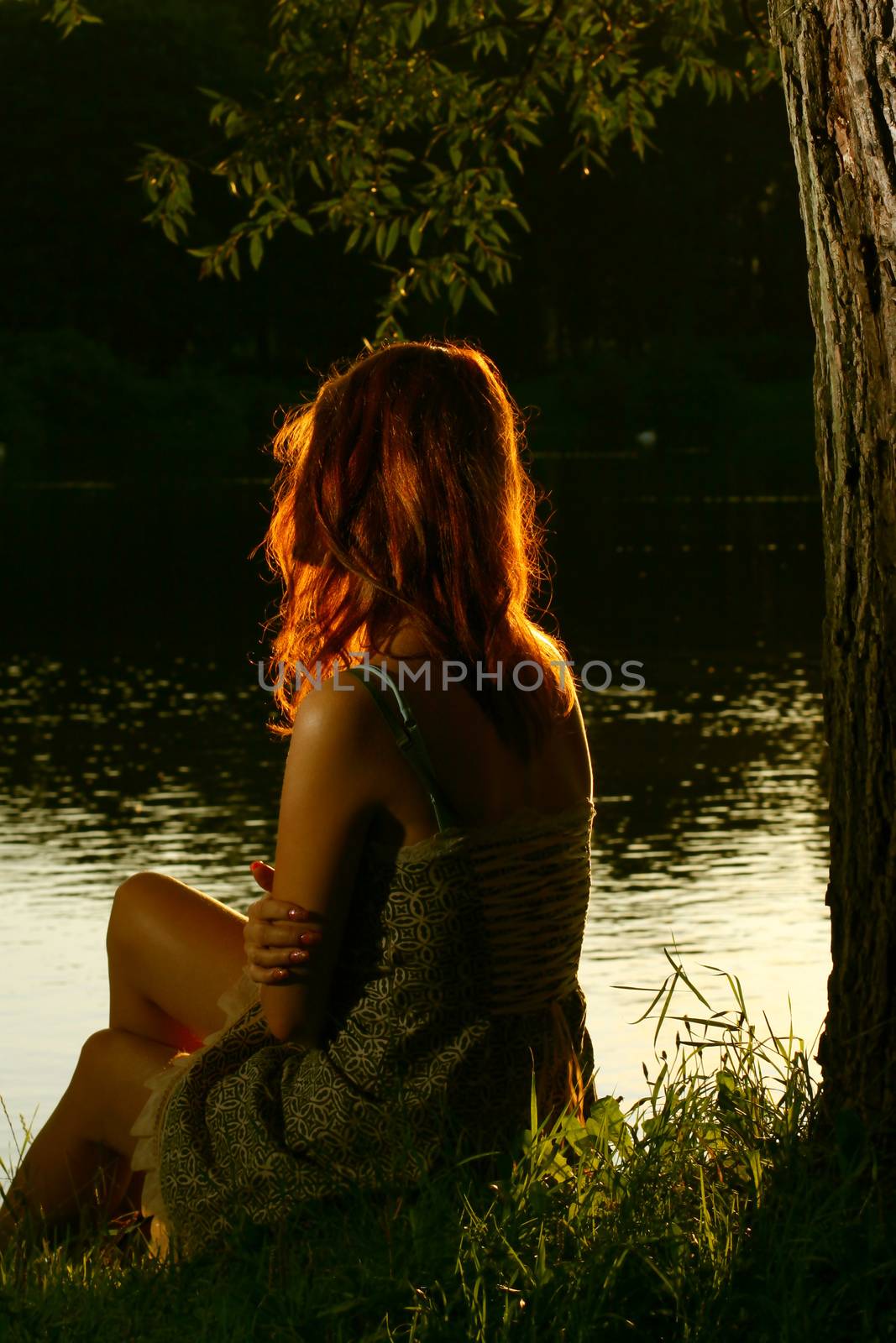 Girl sitting on tha bank of forest river