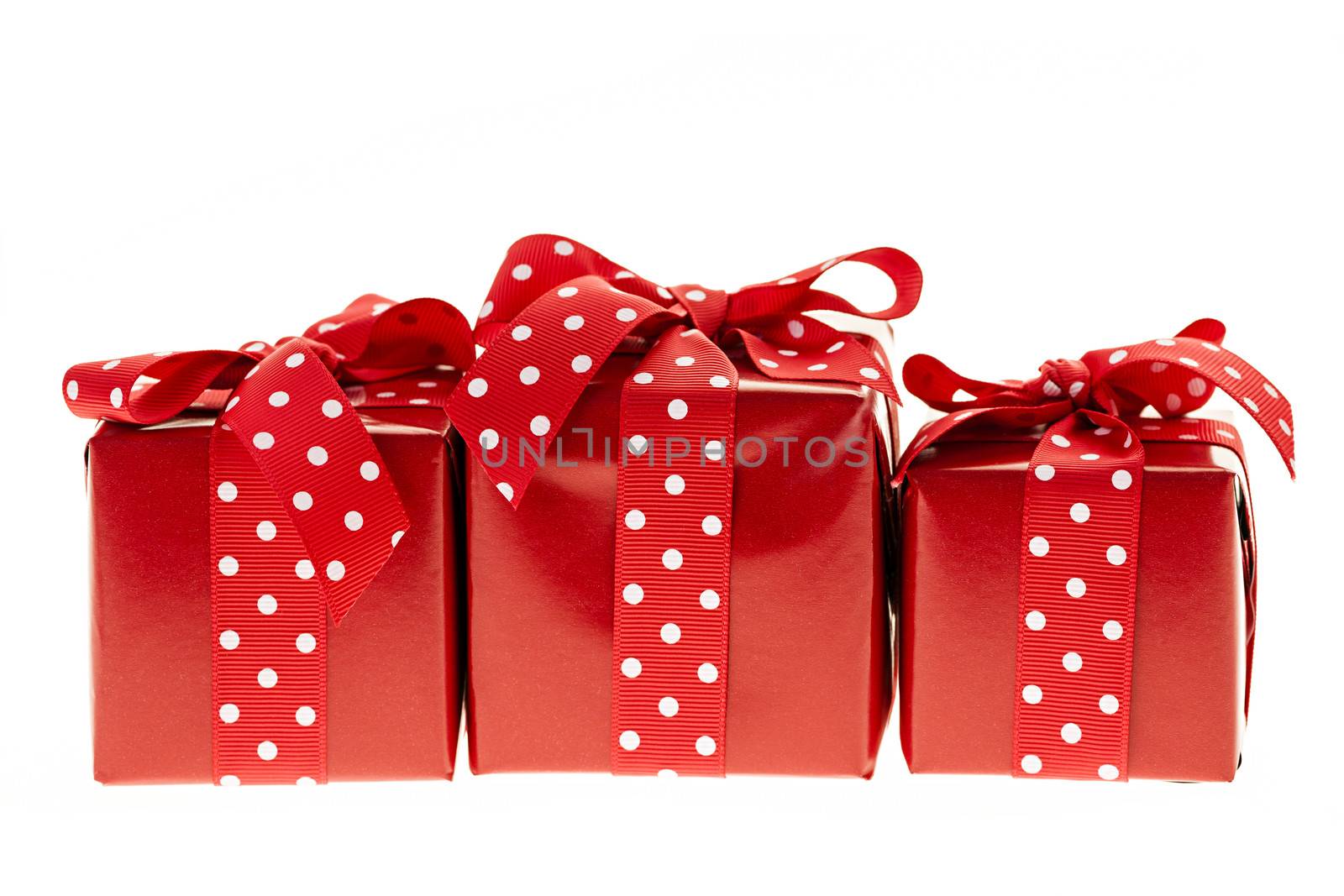 Three presents wrapped in red paper with polkadot ribbon