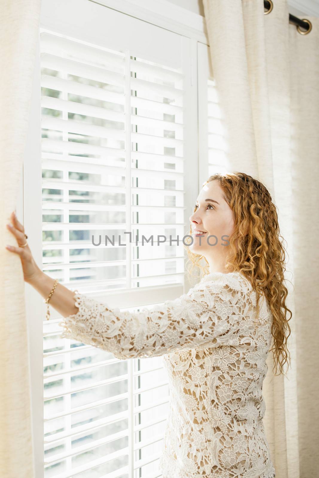 Smiling woman looking out window by elenathewise