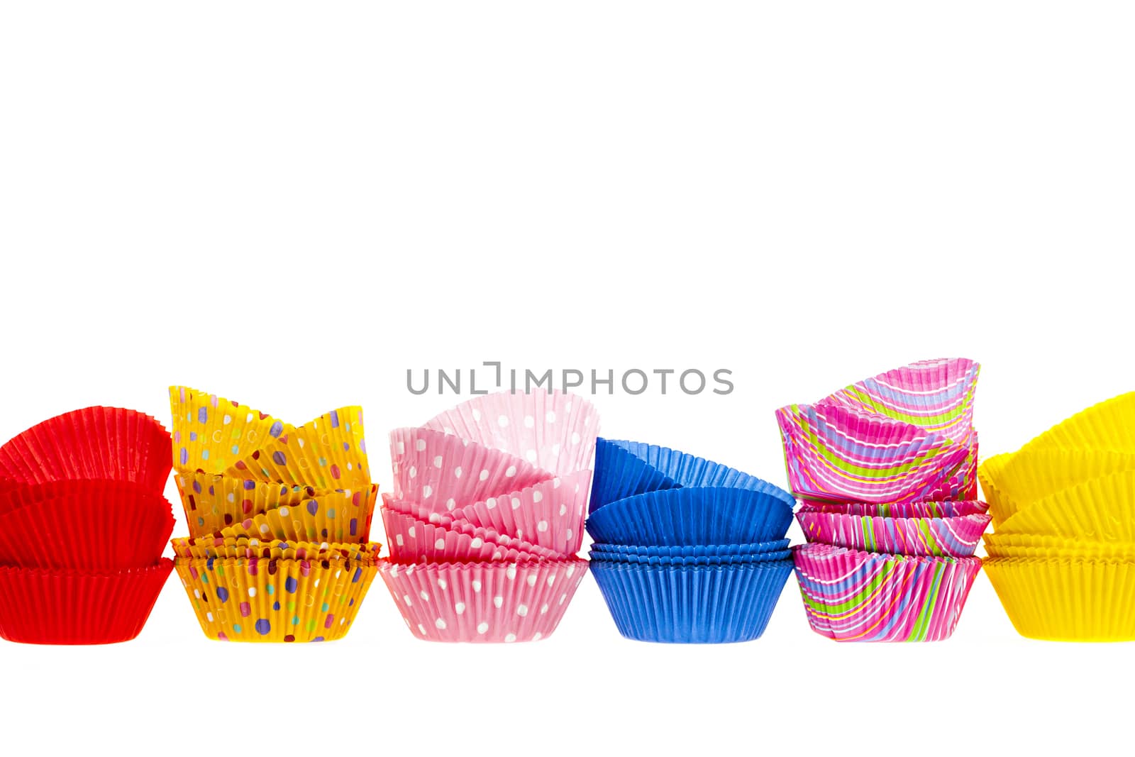 Several stacks of colorful muffin or cupcake cups isolated on white background as border