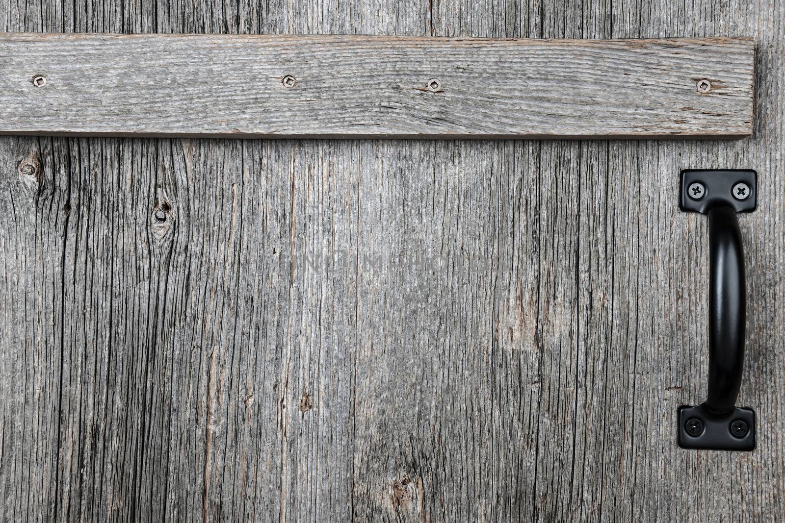 Distressed rustic barn wood door with handle as textured background