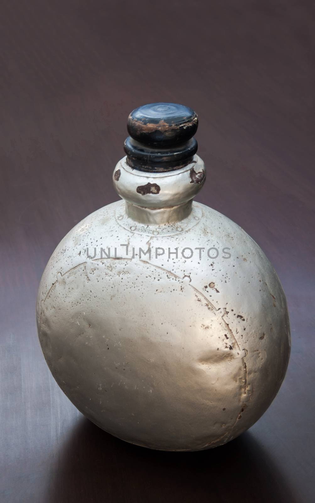 Vertical color portrait in a studio showroom interior displaying old industrial aluminum chemical bottle standing on a occasional table. A generic shot and location was Bombay India, available with property release.