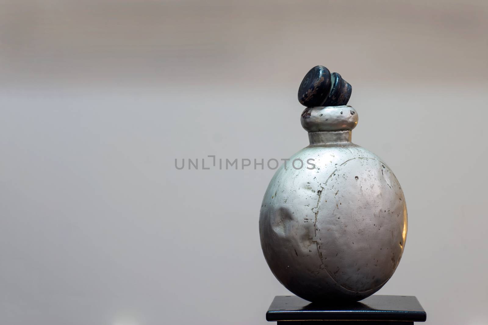 Horizontal color portrait in a studio showroom interior displaying old industrial aluminum chemical bottle standing on an oak table stand plinth. Location for this generic shot was Bombay India, available with property release.