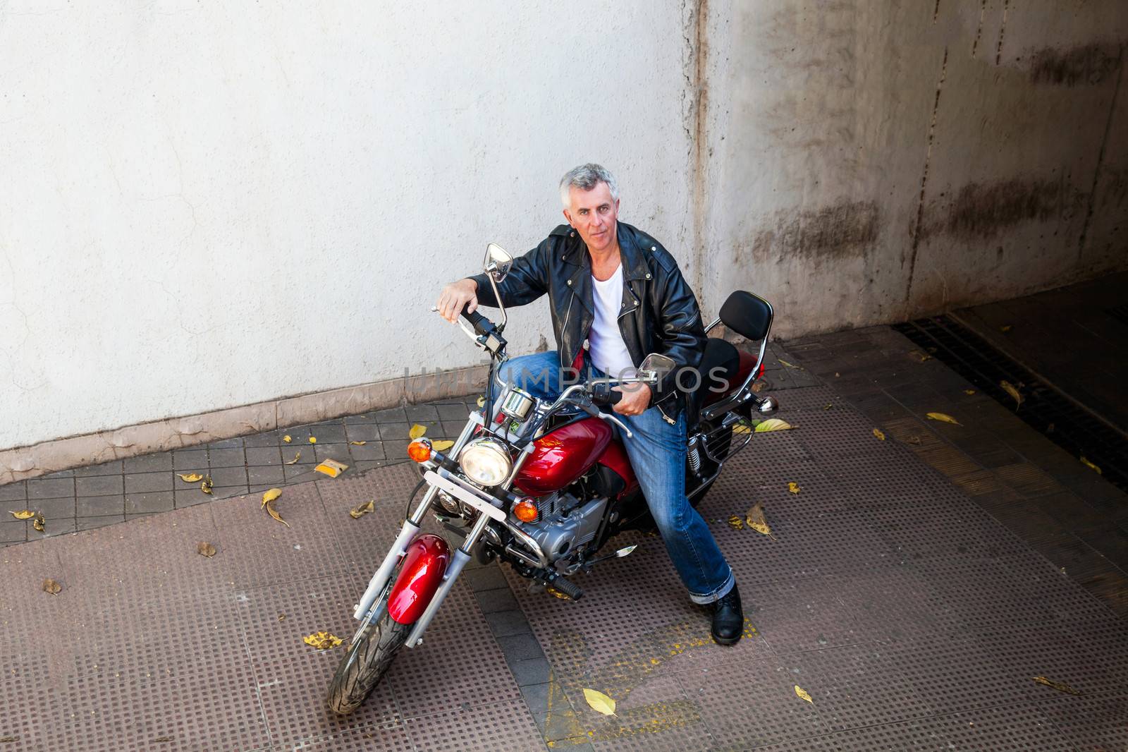 Horizontal color landscape from an elevated POV of a senior gray haired Caucasian motor cycle rider on a red cruiser. Generic shot location in Bombay India. Model release available