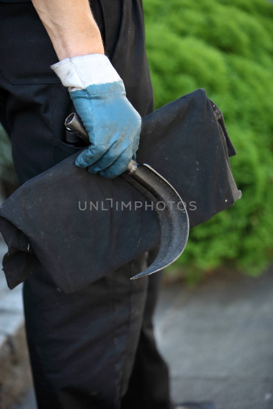 Chimney sweep holding a curved metal scraping tool for dislodging soot and debris from inside a chimney flue