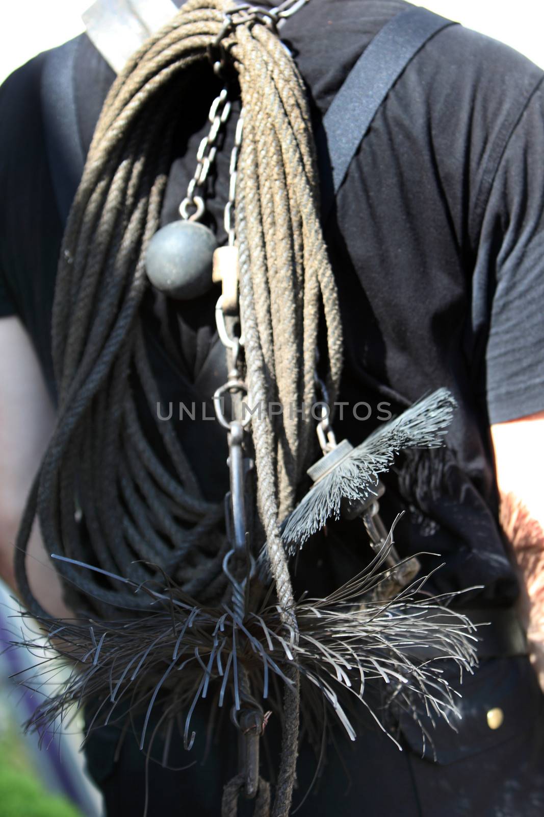 Weighted chain, rope and wire brush for cleaning chimneys being carried on the back of a chimney sweep