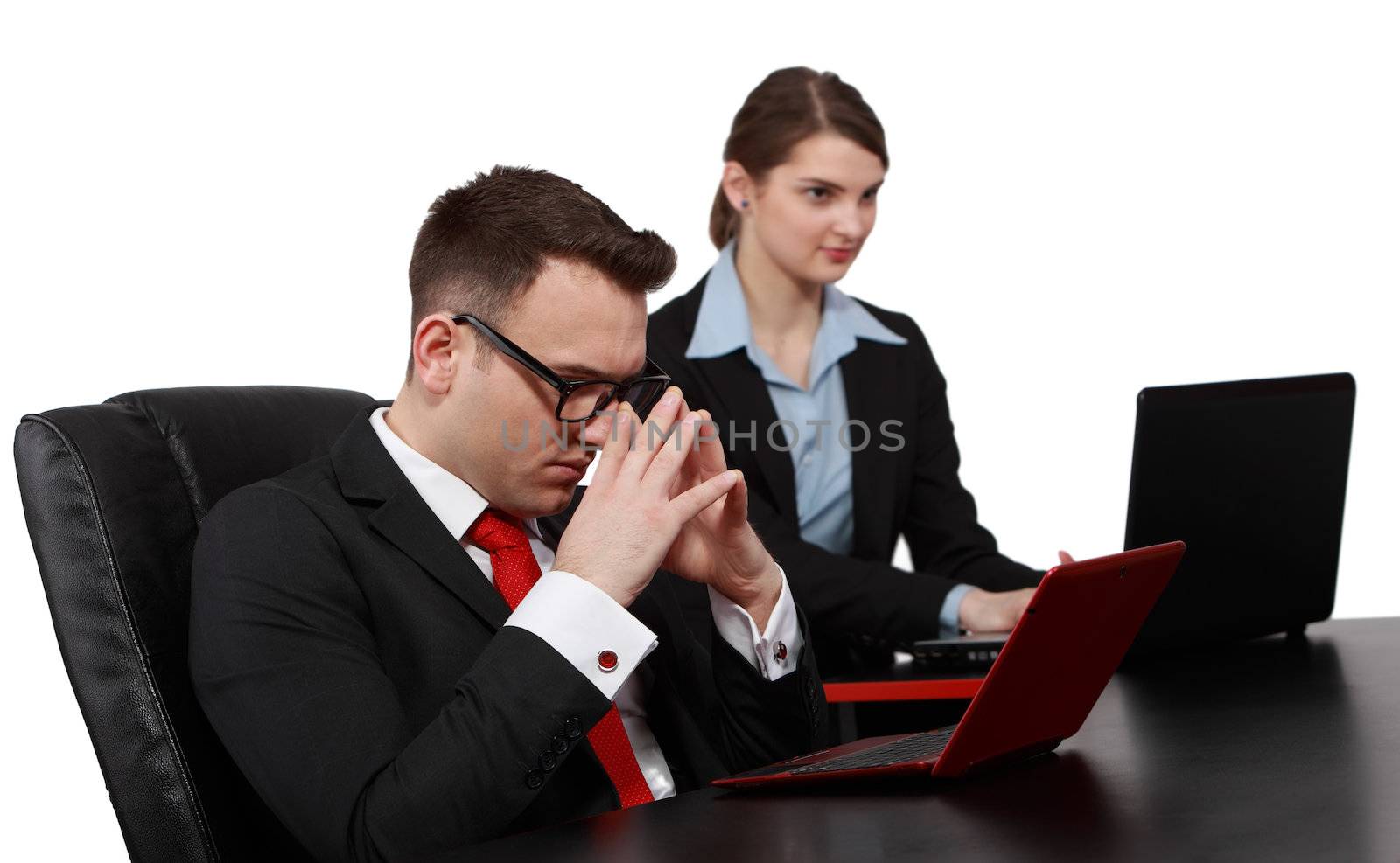 Businessman thinking in front of his notebook near a young female colleague on their desk