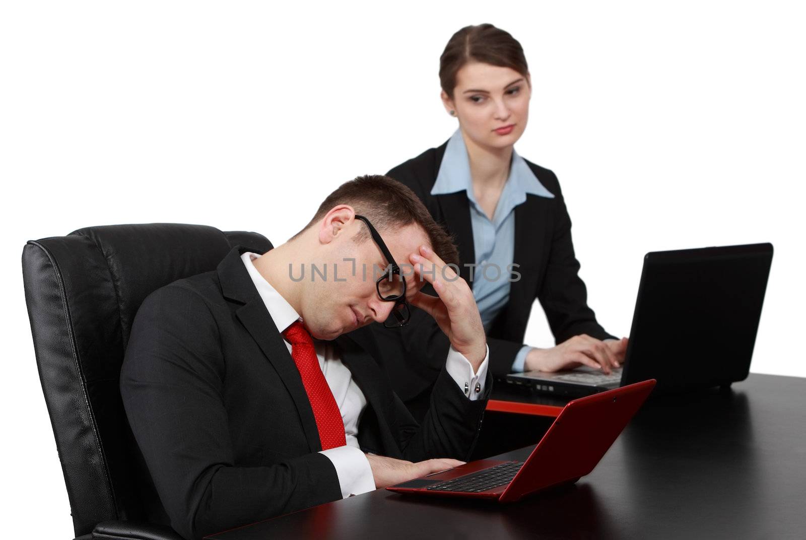 Businessman thinking in front of his notebook near a young female colleague on their desk