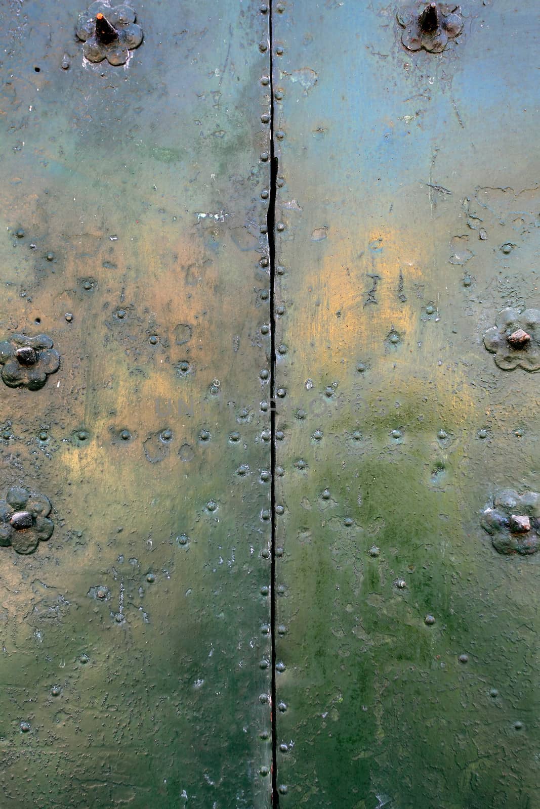 Photo of a green steel plate with rivets.