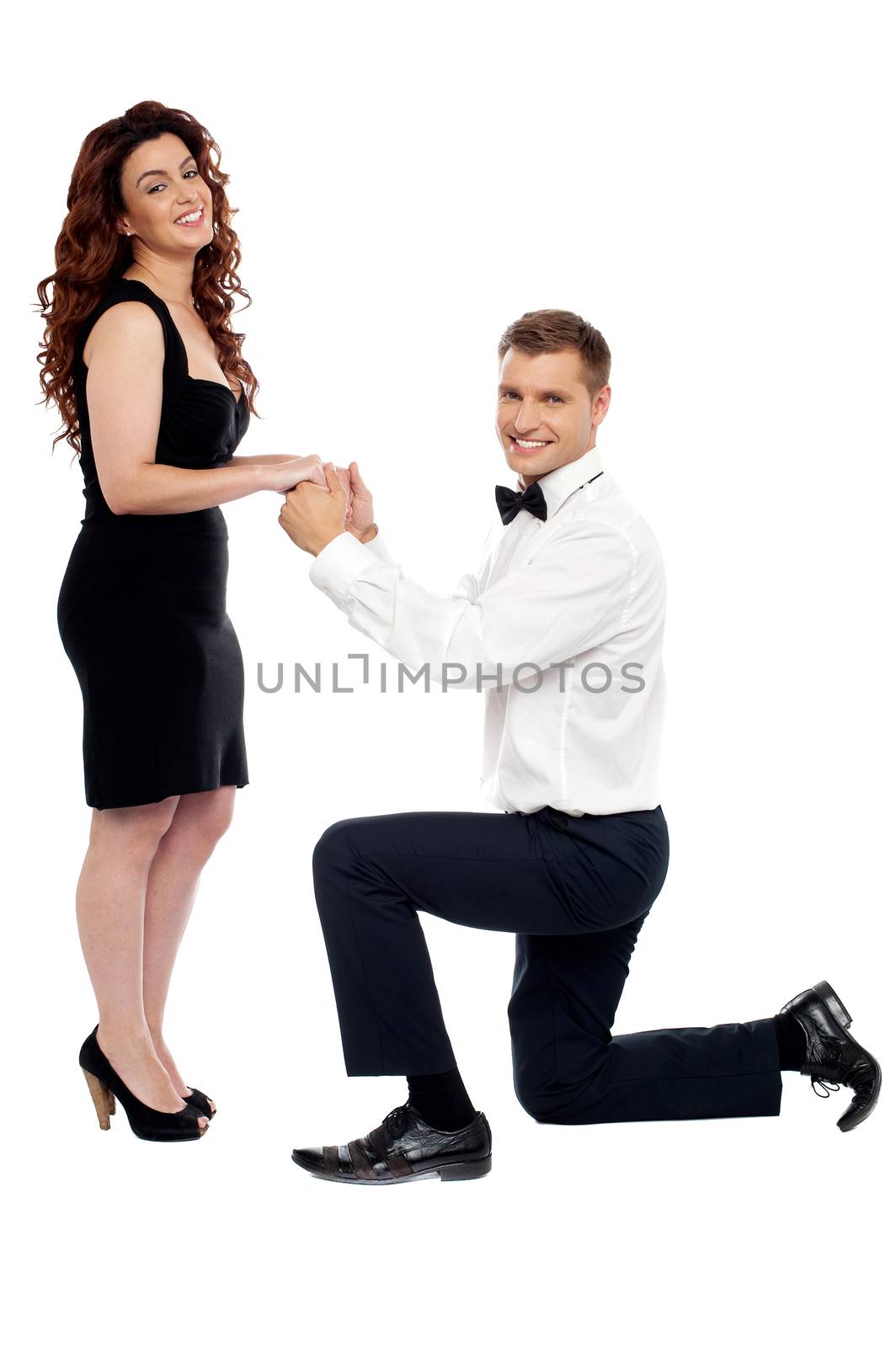 Handsome guy on his knees proposing girl to marry him holding hands of his  beloved