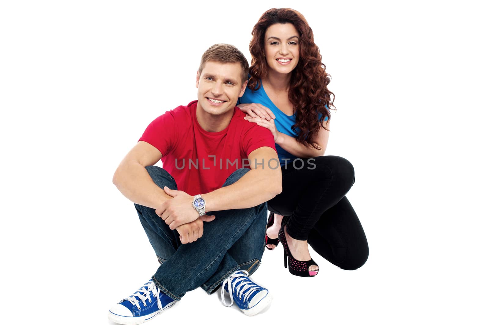 Trendy adorable love couple sitting on floor isolated against white background